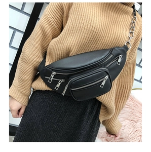 Detail of a chic black leather waist bag with silver chain strap worn by a model