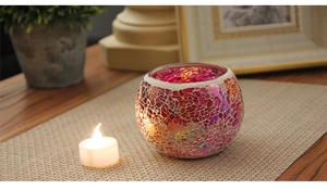 Macro shot of mosaic glass candle holder with warm colorful glow on woven mat
