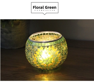 Detail of green mosaic glass candle holder with floral pattern and warm candle glow