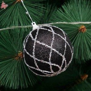 Detail of black Christmas ball with silver glitter diamond pattern on a pine tree