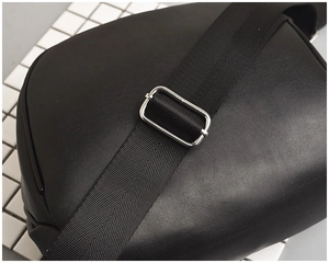 Detail of adjustable black fabric shoulder strap with silver metal buckle on leather bag