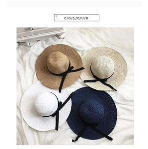 Top view of hand-woven straw sun hats in four colors with black bow ribbon detail