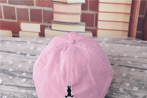 Detailed close-up of a red and white striped baby cap with black rabbit embroidery