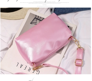 Close-up of pink pearlescent jelly crossbody bag with gold hardware on white fabric