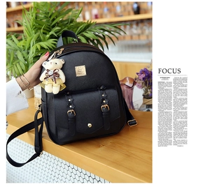 Detail eines schwarzen PU-Lederrucksacks mit Bärenanhänger und Blumen-Schnallenakzent