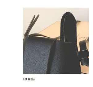 Detail of black litchi grain leather bag showing the top flap and strap attachment