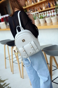 Detailed view of light gray faux leather backpack with floral flap and bear charm