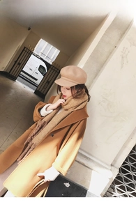 Close-up of a soft mohair dark brown knitted scarf paired with a camel wool coat
