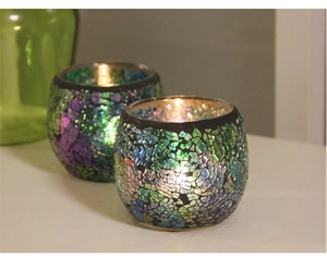 Detailed view of two mosaic glass candle holders with colorful fragments and warm light