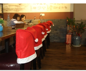 Detail of red Christmas hat chair covers with white fur trim in a festive cafe setting