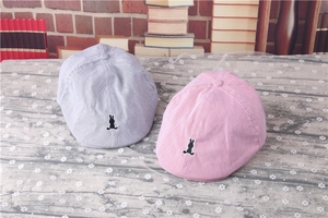 Close-up of pink and grey striped baby beret hats with cute rabbit silhouette embroidery