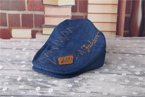 Detail of blue denim baby flat cap with yellow stitching and vintage 1987 leather patch