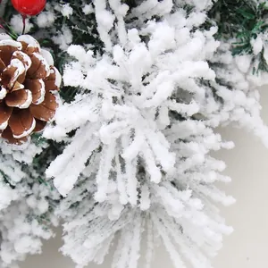 Flocked Christmas wreath with snowy pine needles, natural pinecones and red berries decoration