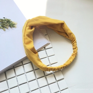 Close-up of a bright yellow twisted headband with soft knit fabric and elastic band