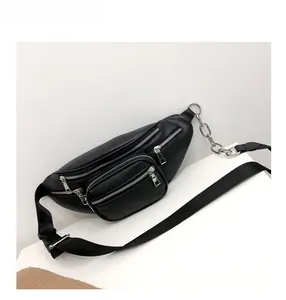Detail of black crossbody waist bag featuring silver metal zippers and decorative chain