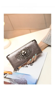 Close-up of metallic long wallet with skull buckle and embossed scroll patterns
