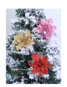 Close-up of glitter hollow artificial poinsettia flowers on a snowy Christmas tree branch