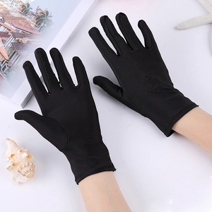 Close-up of black lace sun protection gloves with floral embroidery on white surface