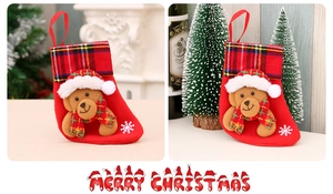 Detail of red Christmas stocking with plush teddy bear, plaid cuff and snowflake patterns