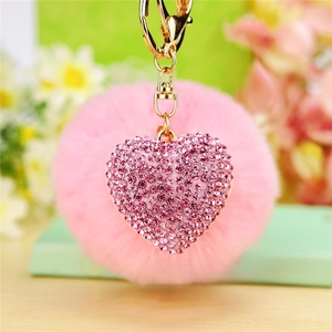 Detailed close-up of a pink faux fur pompom keychain with a sparkling rhinestone heart