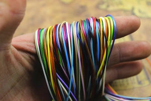 Colorful woven wax cord bundle for DIY jewelry making held in hand for size comparison