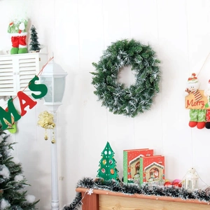 Detail of Christmas wreath with artificial snow needles on white wood background decoration