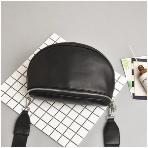 Detail of black leather half-moon crossbody bag with silver zipper and wide nylon strap