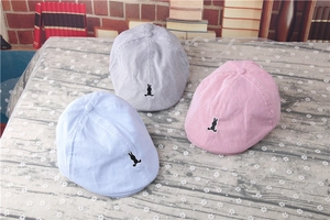 Detailed close-up of striped baby berets in blue, grey, and pink with rabbit embroidery