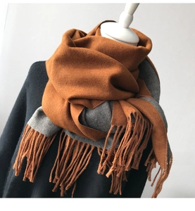 Detail of caramel and grey bicolor cashmere feel scarf with long tassels for winter