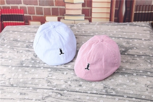 Close-up of pink and blue striped baby berets with cute bunny embroidery detail