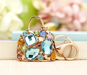 Detail of a gold bag-shaped keychain featuring vibrant multicolor rhinestones and lobster clasp