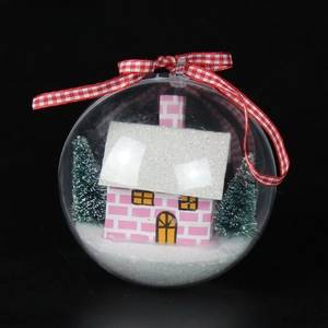 Close-up of clear Christmas ornament with pink miniature house and fake snow decor