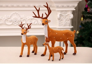 Three realistic reindeer figurines in various sizes on a festive mantelpiece setup