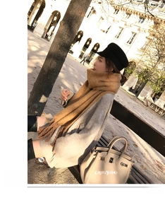 Outdoor shot of a thick camel mohair scarf with tassels paired with a grey knit sweater