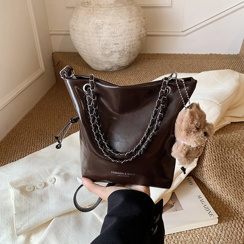 Damen Glänzende PU Leder Eimer-Tasche Vielseitige Metallkette Schulter Crossbody Bag Mit Bären-Anhänger Mode Pendeln Handtasche