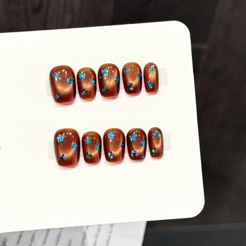 Handgefertigte Karamellbraun Katzenauge Künstliche Nägel Mit Blauer Glitzerblume Kurze Sargform Kunstnägel Set Für Damen