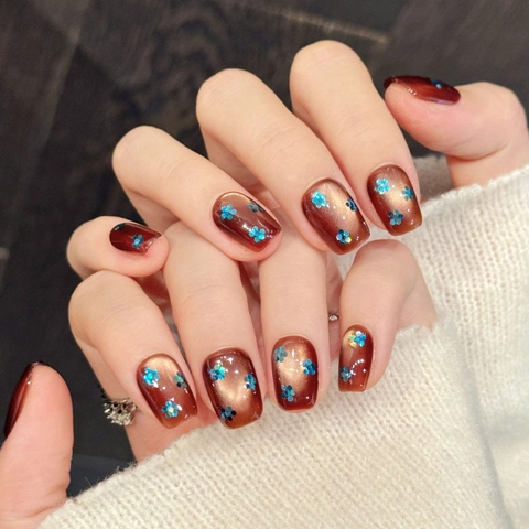 Handgefertigte Karamellbraun Katzenauge Künstliche Nägel Mit Blauer Glitzerblume Kurze Sargform Kunstnägel Set Für Damen