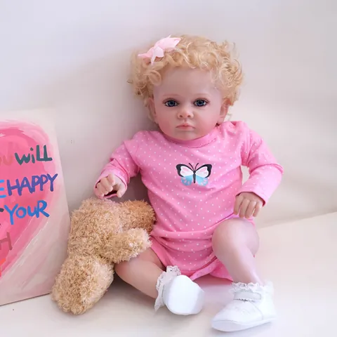 Poupée Reborn Réaliste 60cm Membres en Silicone Souple Corps en Coton Barboteuse Rose à Pois Papillon Cheveux Bouclés Or Yeux Bleus Peinte à la Main