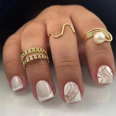 Unghie Finte Style Francese Corte Quadrate Rosa Nude Con Linee Ondulate Dorate E Punte Bianche Eleganti Donna